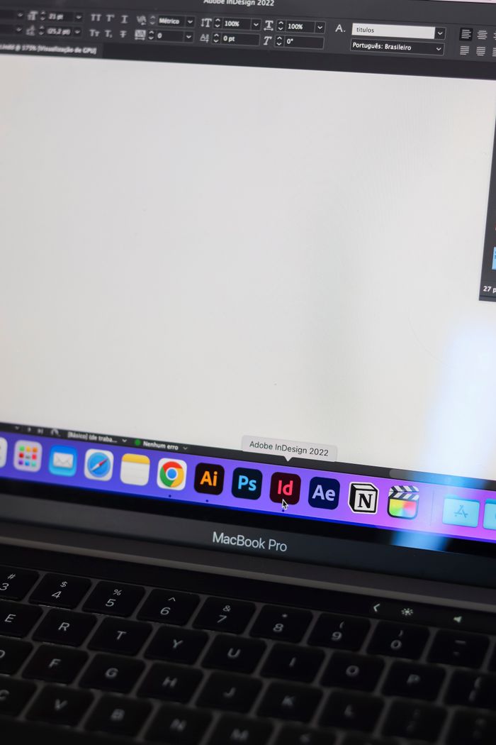 hero-img-01 A detailed view of a MacBook Pro displaying Adobe InDesign and other design tools on screen.